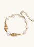 Delicate 14K gold plated bracelet with freshwater pearls and ribbed gold elements on cream background.