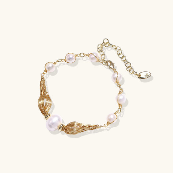 Delicate 14K gold plated bracelet with freshwater pearls and ribbed gold elements on cream background.