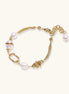 Gold-plated bracelet featuring cream freshwater pearls and decorative chain links on white background.