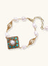 Ornate gold-plated bracelet with square turquoise and crystal centerpiece, freshwater pearls, and decorative chain links