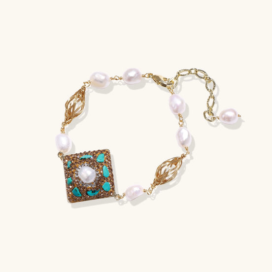 Ornate gold-plated bracelet with square turquoise and crystal centerpiece, freshwater pearls, and decorative chain links