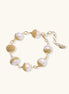 Adjustable bracelet featuring baroque pearls wrapped in gold mesh wire with delicate chain links on cream background.