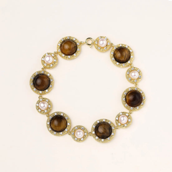 Ornate gold-plated bracelet with alternating brown tiger's eye stones and white freshwater pearls in crystal-accented settings