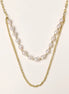 Layered gold chain necklace with irregular freshwater pearls on cream background, showing adjustable dual-strand design.