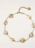 Delicate gold chain bracelet featuring iridescent shell charms with freshwater pearls on white background.