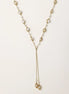 Long gold-plated lariat necklace with wire-wrapped freshwater pearls and chain tassel detail on cream background.