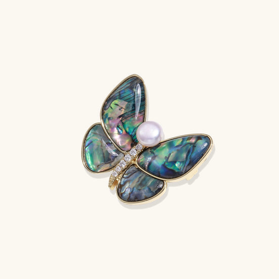 Iridescent abalone shell butterfly pin with central pearl and gold setting, showing rainbow color reflections