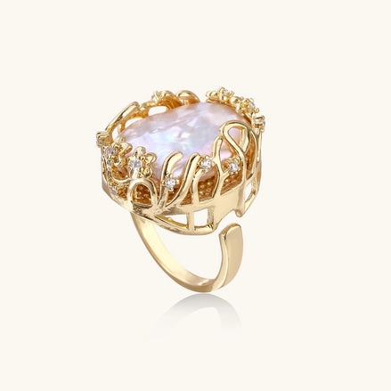 Ornate gold-plated ring with large baroque pearl in decorative vine-like setting with small crystal accents