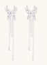 Elegant silver-plated drop earrings with wing-shaped tops, white pearl accents, and long chain tassels on white background.