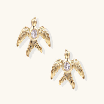Pair of gold-plated eagle stud earrings with spread wings and purple zirconia center stones on white background.