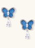 Silver-toned butterfly earrings with blue enamel wings and crystal drop pendants on white background.