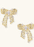 Gold and silver bow-shaped earrings with intricate lattice pattern and clear zirconia stones on neutral background.