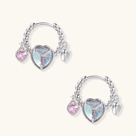Gold-plated brass hoop earrings with three heart charms including iridescent turquoise and pink hearts on white background.
