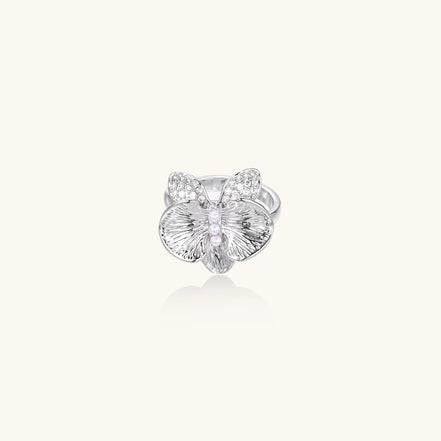 Gold-plated brass ring with textured orchid petals, zirconia stones, and center pearls on white background.