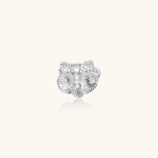 Gold-plated brass ring with textured orchid petals, zirconia stones, and center pearls on white background.