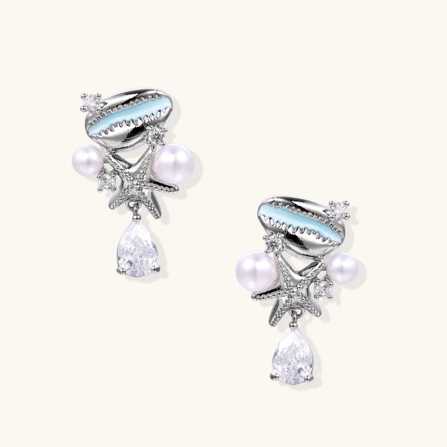 Gold-plated dangle earrings with enamel shell charms, white pearls, starfish accents, and crystal drops on white background.
