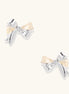 Close-up of bow-shaped stud earrings with 18K gold plated brass and silver details on white background.