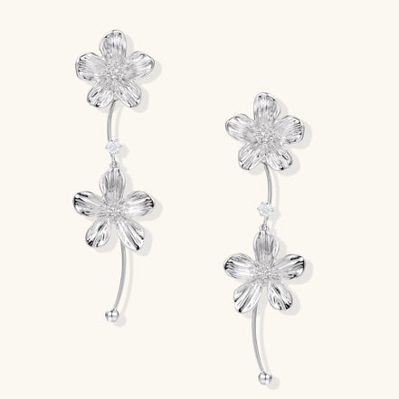 Gold-plated floral dangle earrings with zirconia crystal centers and curved stems on white background.