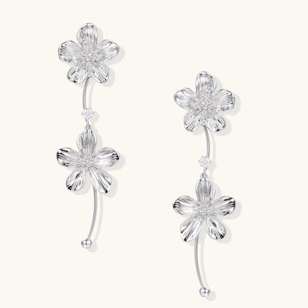 Gold-plated floral dangle earrings with zirconia crystal centers and curved stems on white background.