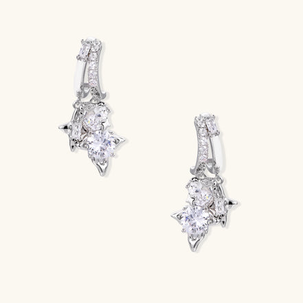 Pair of gold-plated drop earrings featuring cascading zirconia crystals in geometric cluster design on neutral background