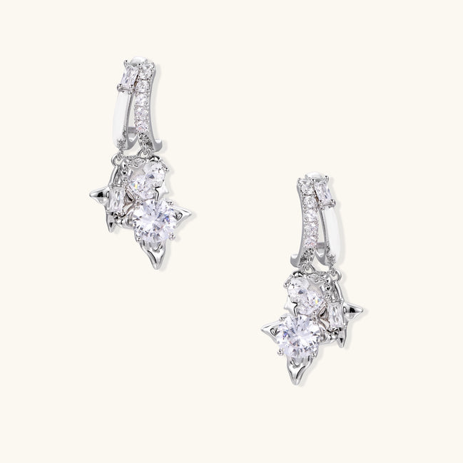 Pair of gold-plated drop earrings featuring cascading zirconia crystals in geometric cluster design on neutral background