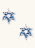Silver-toned floral earrings with blue denim fabric petals, white pearls, and crystal accents on cream background.