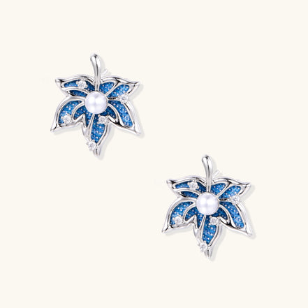 Silver-toned floral earrings with blue denim fabric petals, white pearls, and crystal accents on cream background.