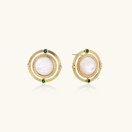 Close-up of gold-plated circular earrings with white mother-of-pearl centers and green zirconia accents on cream background.