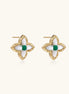 Dainty gold-plated quatrefoil stud earrings with white mother-of-pearl petals and green gemstone centers on beige background.