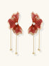 Statement drop earrings with coral-red enamel flower petals, gold-plated brass, and mother-of-pearl centers on white background