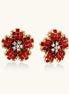 Gold-plated floral stud earrings with layered red crystal petals and clear zirconia centers on cream background.