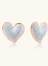 Heart-shaped stud earrings with iridescent blue-pink enamel finish and gold-plated brass frames against cream background