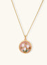 Gold-plated pendant necklace with pink enamel background and white freshwater pearl floral design on neutral background.