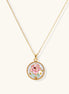 Gold-plated circular pendant featuring pink enamel rose with pearl accents and green leaf details on adjustable chain.