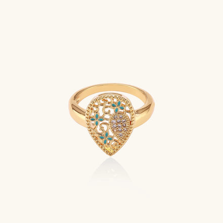 Gold-plated heart ring with turquoise enamel scrollwork and cubic zirconia stones on white background