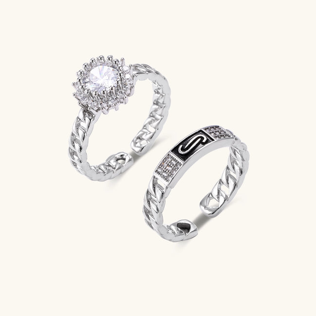 Two gold-plated rings with chain-link bands, one featuring cubic zirconia halo setting, displayed on neutral background
