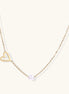 Dainty 14K gold-plated necklace with open heart pendant and white pearl bead on neutral background
