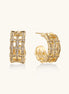 Close-up of geometric gold-plated hoop earrings with crystal pave in intricate lattice pattern on neutral background.