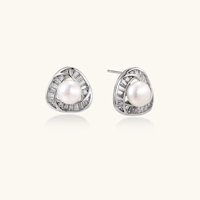 Close-up of triangular gold-plated stud earrings with central freshwater pearl surrounded by baguette crystals