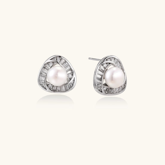Close-up of triangular gold-plated stud earrings with central freshwater pearl surrounded by baguette crystals