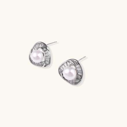 Close-up of triangular gold-plated stud earrings with central freshwater pearl surrounded by baguette crystals
