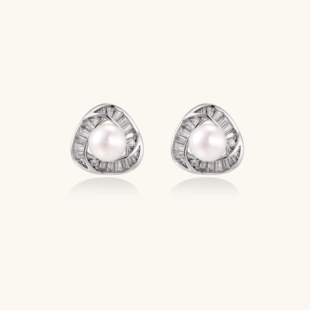 Close-up of triangular gold-plated stud earrings with central freshwater pearl surrounded by baguette crystals