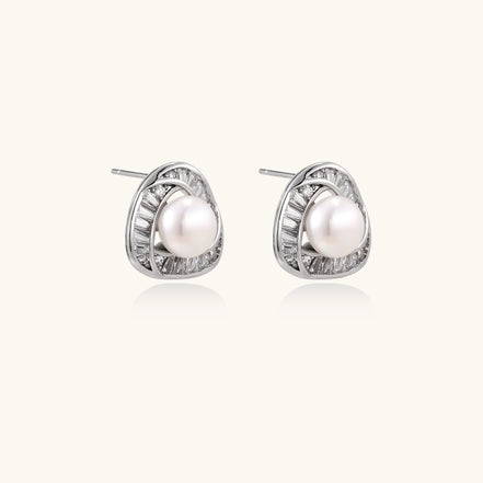Close-up of triangular gold-plated stud earrings with central freshwater pearl surrounded by baguette crystals