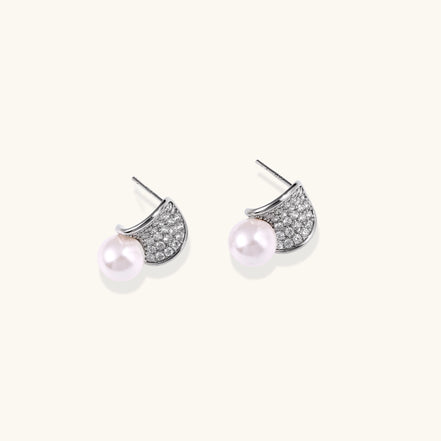 Elegant gold-plated curved earrings with diamond pavé crescents and suspended freshwater pearls on neutral background.