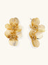 Layered gold-plated floral stud earrings with textured petals and crystal-accented centers on white background.