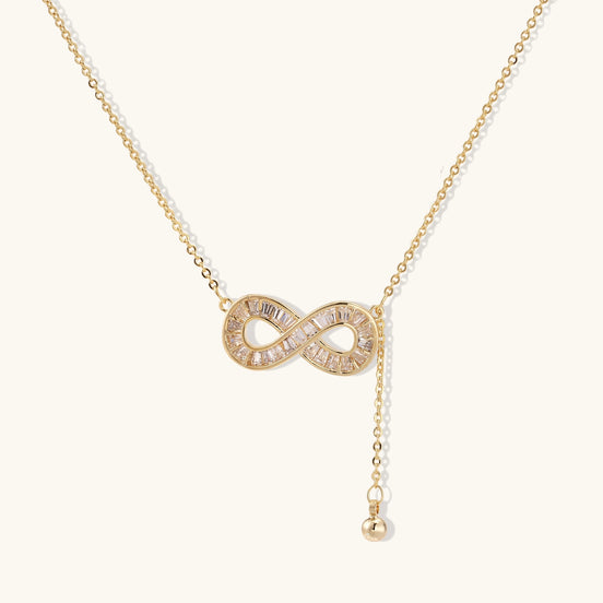Delicate 14K gold plated infinity pendant with crystal accents on adjustable chain with small ball charm detail.