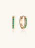Small gold-plated huggie hoop earrings with emerald green cubic zirconia stones, one open showing hinge mechanism