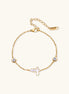 Delicate gold-plated bracelet featuring white mother-of-pearl cross charm and crystal accents on white background.