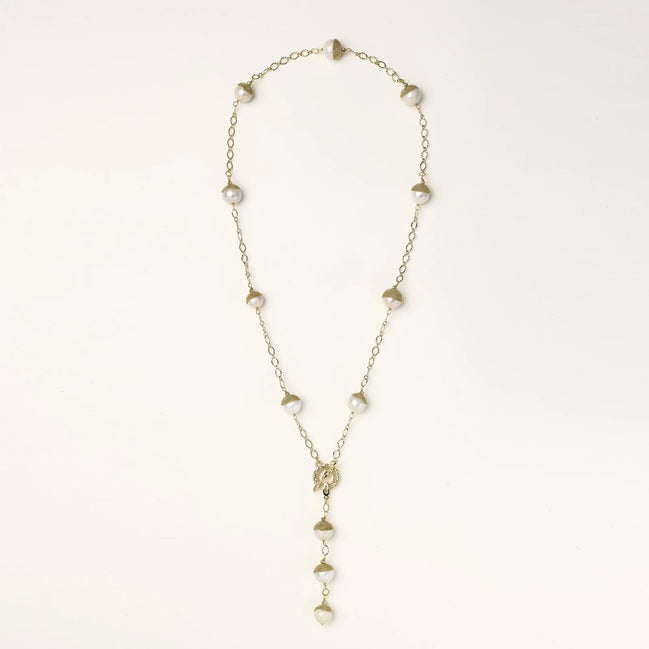 Gold-plated lariat necklace with baroque pearls and textured caps on cream background, showing adjustable Y-shaped design.
