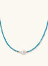 Delicate gold vermeil necklace with teal apatite beads and freshwater pearl on white background.